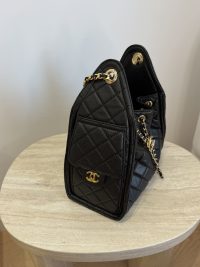 Black Chanel bag with chain on wooden table.