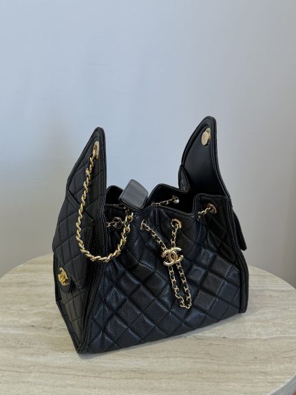 Black Chanel bag with gold chain on table.