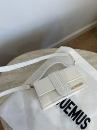 White Jacquemus Le Bambino mini bag on branded dust bag.