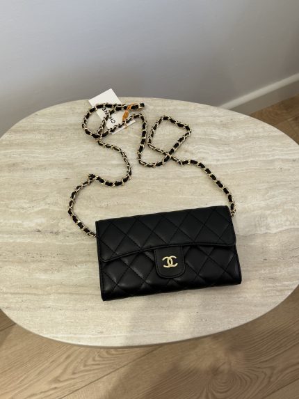 Black quilted mini Chanel bag with chain on table.