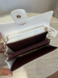 Open white Chanel mini bag with chain and burgundy interior.