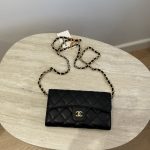 Black quilted mini Chanel bag with chain on table.