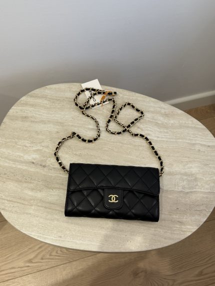 Black quilted mini Chanel bag with chain on table.