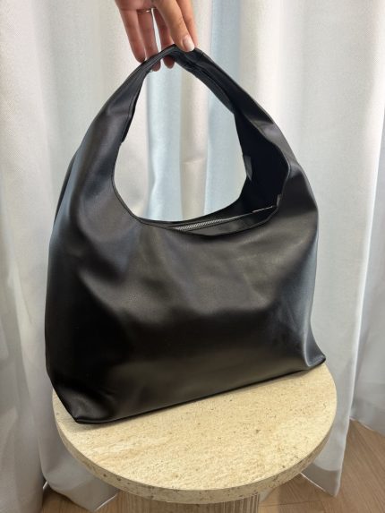 Large black leather hobo bag on round table.