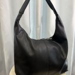 Elegant black leather university handbag on display table.