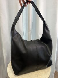 Elegant black leather university handbag on display table.
