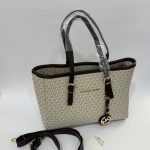 Michael Kors beige tote bag with brown straps and logo charm.