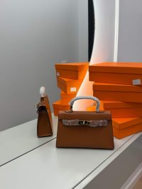 Hermès Mini Kelly bag with orange boxes on white surface.