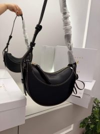 Polène Cyme Mini black handbag displayed elegantly in a mirror.