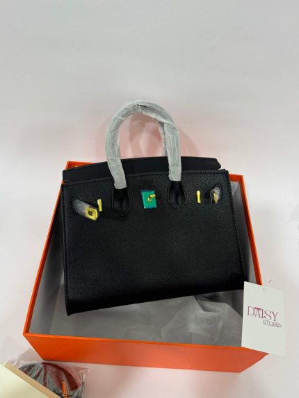 Black Hermès Birkin handbag in orange box, elegant luxury style.