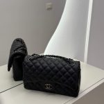 Black Chanel Classic Flap bag on mirrored surface.