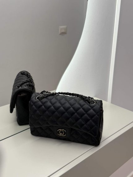 Black Chanel Classic Flap bag on mirrored surface.