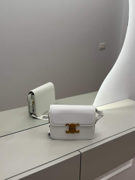 White Céline Triomphe bag on mirrored surface, elegant and versatile design.