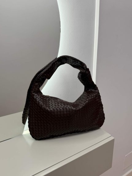 Elegant woven hobo bag with knotted handle on display.