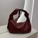Elegant woven hobo bag with knotted design in rich burgundy color.