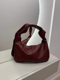 Elegant woven hobo bag with knotted design in rich burgundy color.