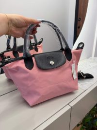 Pink Longchamp Le Pliage bag with black handles displayed elegantly.