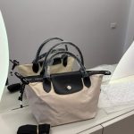 Çanta Longchamp Le Pliage beige tote on display with black handles.