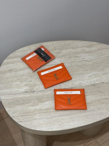 Orange YSL card holders on a marble table.