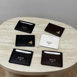 Prada Saffiano card holders in black, white, and brown on table.