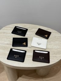 Prada Saffiano card holders in black, white, and brown on table.