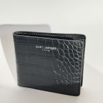 Black Saint Laurent croc-embossed wallet on white background.