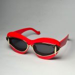 Red Loewe cat-eye sunglasses with gold accents on white background.
