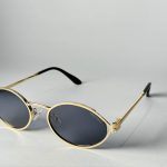Miu Miu gold metal sunglasses with round lenses on display.