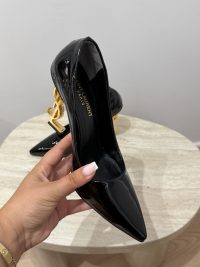 Black patent leather heels with gold YSL logo heel detail.