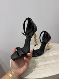 Black YSL Opyum sandals with gold logo heels on display.