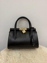 Dolce & Gabbana black handbag with gold accents on table.