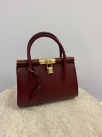Dolce & Gabbana red handbag with gold frame on table.
