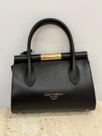 Black Dolce & Gabbana handbag with gold accents on display.