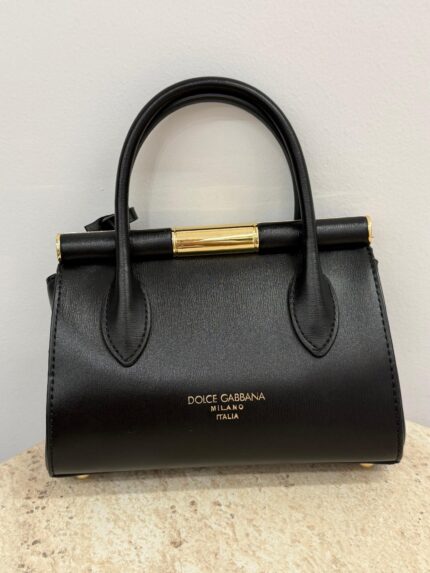 Black Dolce & Gabbana handbag with gold accents on display.