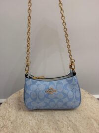 Blue Coach Teri Shoulder Bag with gold chain on table.