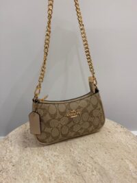 Coach Teri Shoulder Bag with gold chain on marble surface.