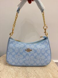 Blue Coach handbag with gold chain and zipper.