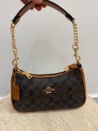 Elegant Coach handbag with handle and chain, stylish design.