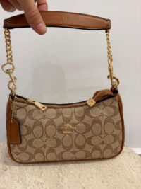 Coach handbag with chain strap and signature pattern.