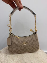 Elegant Coach handbag with handle and chain, stylish design.
