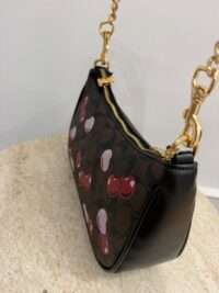 Çanta femrash Coach me qershi, elegancë dhe stil, me zinxhir ari.