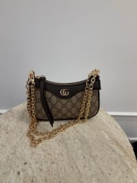 Gucci Aphrodite GG handbag with gold chain on table.