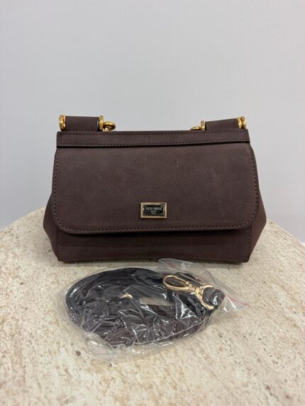Dolce & Gabbana brown handbag with gold accents on table.
