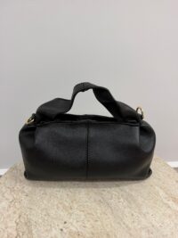 Black Polène leather handbag on beige surface.