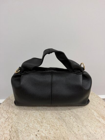 Black Polène leather handbag on beige surface.