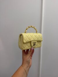 Chanel Mini Flap yellow quilted handbag with gold chain handle.