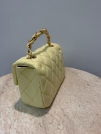 Chanel Mini Flap bag with gold chain on marble surface.