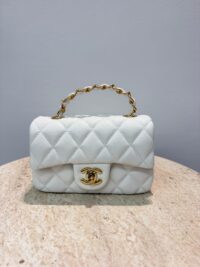 Chanel Mini Flap bag with gold chain on marble surface.