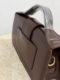 Brown Jacquemus Le Bambino Long handbag on marble surface.