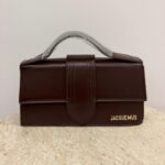 Brown Jacquemus Le Bambino Long handbag on textured surface.